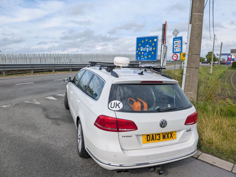 An estate car with a roof-mounted bonded antenna dome at the Belgian border.